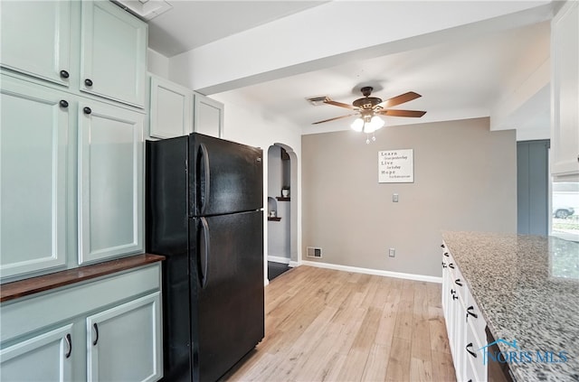 1447 Craigwood Rd, Toledo, OH 43612 - kitchen with freestanding refrigerator, ceiling fan, light wood finished floors, dark stone counters, and arched walkways