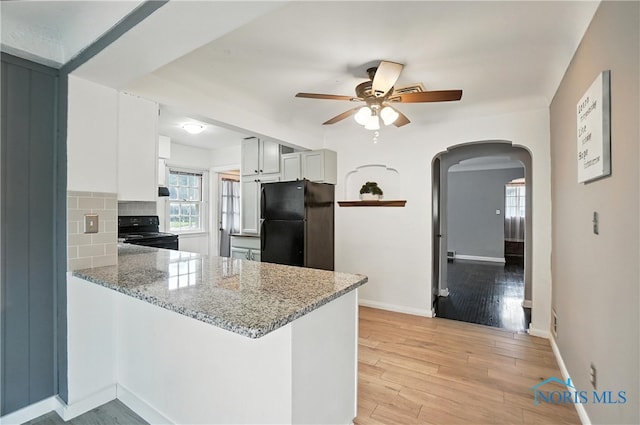 1447 Craigwood Rd, Toledo, OH 43612 - kitchen featuring black appliances, a ceiling fan, arched walkways, a peninsula, and light stone counters