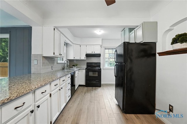 1447 Craigwood Rd, Toledo, OH 43612 - kitchen featuring black appliances, light wood finished floors, under cabinet range hood, light stone countertops, and white cabinetry