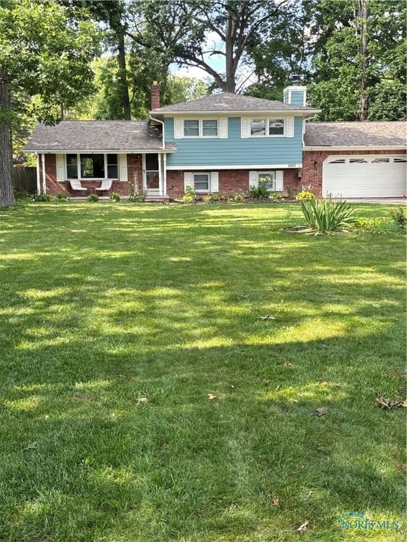 2920 Copland Blvd, Toledo, OH 43614 - tri-level home featuring a chimney, an attached garage, and a front yard