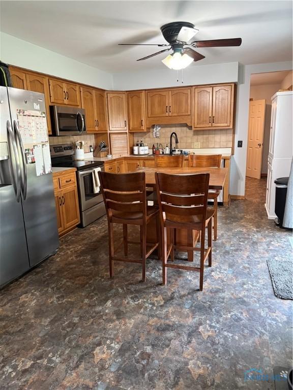 1819 Queenswood Dr, Findlay, OH 45840 - kitchen with appliances with stainless steel finishes, ceiling fan, decorative backsplash, and brown cabinets