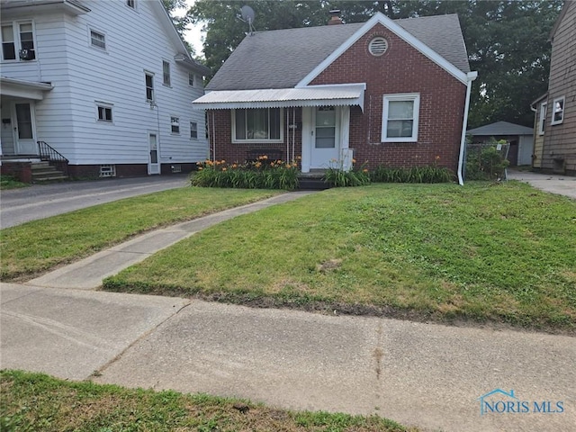 2127 Perth St, Toledo, OH 43607 - bungalow-style home featuring brick siding, a front lawn, and roof with shingles