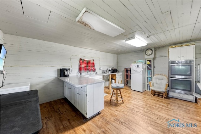 22804 State Route 2, Archbold, OH 43502 - kitchen featuring stainless steel double oven, a peninsula, freestanding refrigerator, a kitchen breakfast bar, and light countertops