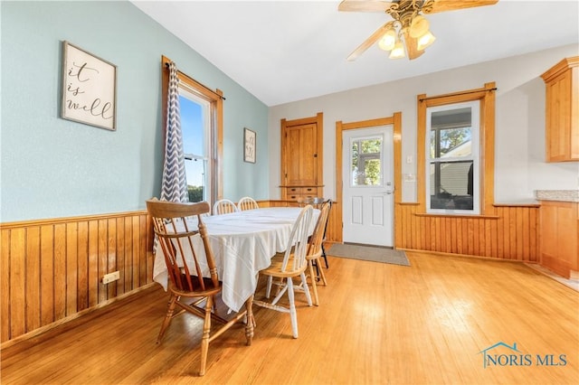 22804 State Route 2, Archbold, OH 43502 - dining room featuring a wainscoted wall, light wood-style flooring, a ceiling fan, and wood walls