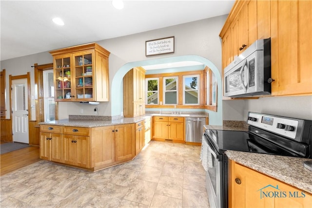 22804 State Route 2, Archbold, OH 43502 - kitchen featuring stainless steel appliances, arched walkways, light stone countertops, glass insert cabinets, and recessed lighting