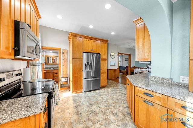 22804 State Route 2, Archbold, OH 43502 - kitchen with appliances with stainless steel finishes, arched walkways, light stone countertops, recessed lighting, and brown cabinets