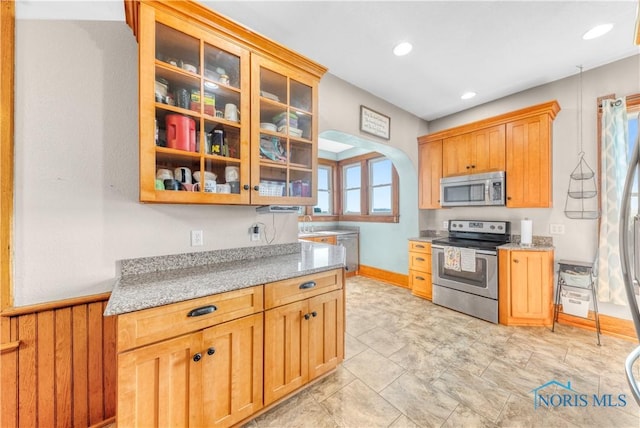 22804 State Route 2, Archbold, OH 43502 - kitchen with appliances with stainless steel finishes, light stone counters, glass insert cabinets, recessed lighting, and arched walkways