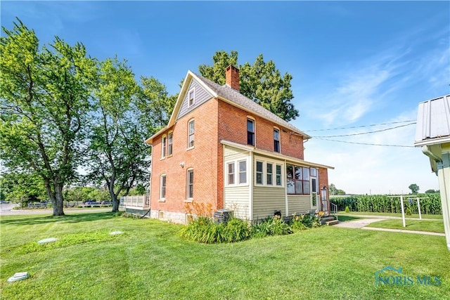 22804 State Route 2, Archbold, OH 43502 - view of home's exterior featuring a chimney, a lawn, brick siding, and entry steps