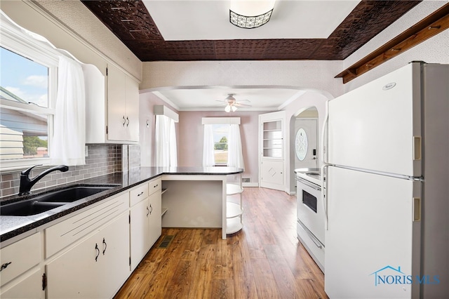 212 18th St, Findlay, OH 45840 - kitchen with white appliances, light wood-style flooring, arched walkways, a peninsula, and white cabinets