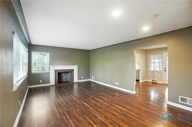 2838 Secor Rd, Toledo, OH 43606 - unfurnished living room with arched walkways, wood finished floors, a fireplace, and plenty of natural light