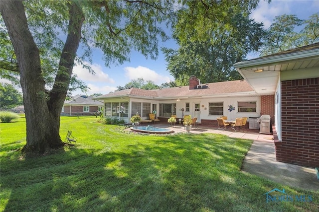 3468 Hughes Blvd, Toledo, OH 43606 - back of house featuring brick siding, a lawn, a patio area, and a chimney