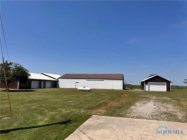 8320 Openlander Rd, Sherwood, OH 43556 - view of green lawn featuring a garage, an outdoor structure, and an outbuilding