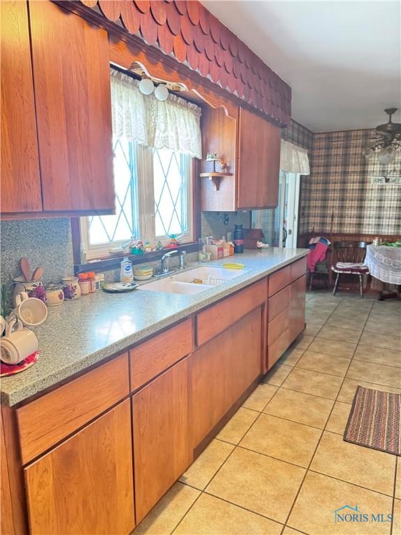 8320 Openlander Rd, Sherwood, OH 43556 - kitchen with wallpapered walls, light tile patterned flooring, brown cabinets, and light stone counters