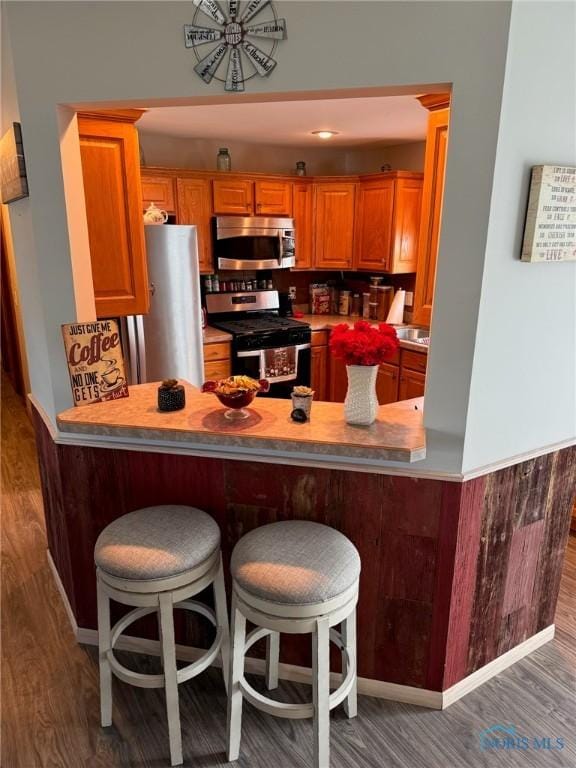 110 Town Line Rd, Bryan, OH 43506 - kitchen with appliances with stainless steel finishes, a peninsula, wood finished floors, and a kitchen bar