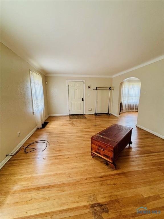 4136 Berwick Ave, Toledo, OH 43612 - living room featuring arched walkways, plenty of natural light, light wood-style flooring, and ornamental molding