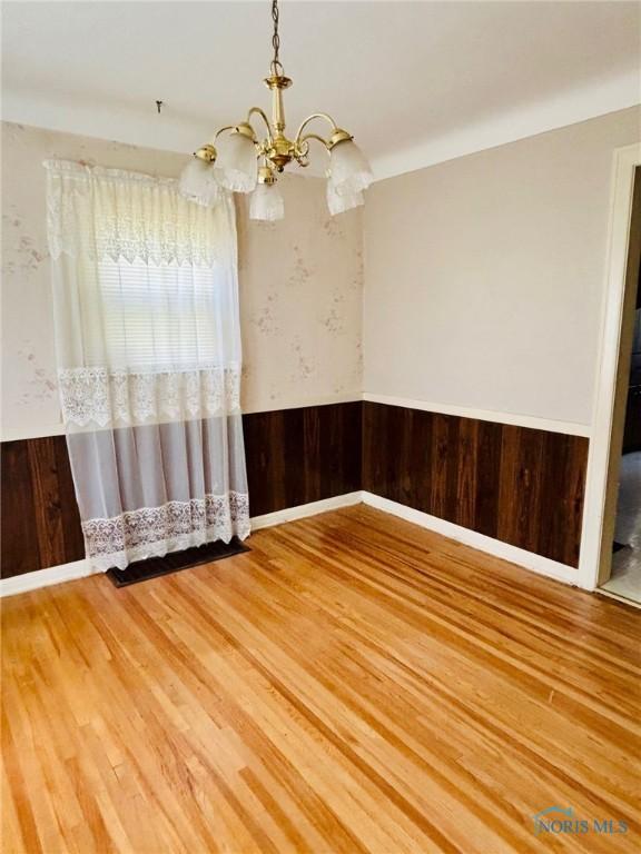 4136 Berwick Ave, Toledo, OH 43612 - empty room featuring a chandelier, wainscoting, and wood finished floors
