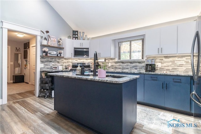 8411 Larch Rd, Toledo, OH 43617 - kitchen with appliances with stainless steel finishes, blue cabinets, light wood finished floors, lofted ceiling, and a center island with sink
