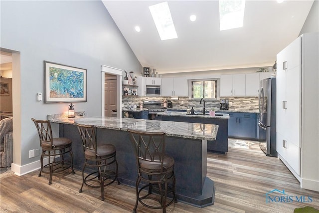 8411 Larch Rd, Toledo, OH 43617 - kitchen with stainless steel appliances, a peninsula, a breakfast bar area, stone countertops, and tasteful backsplash