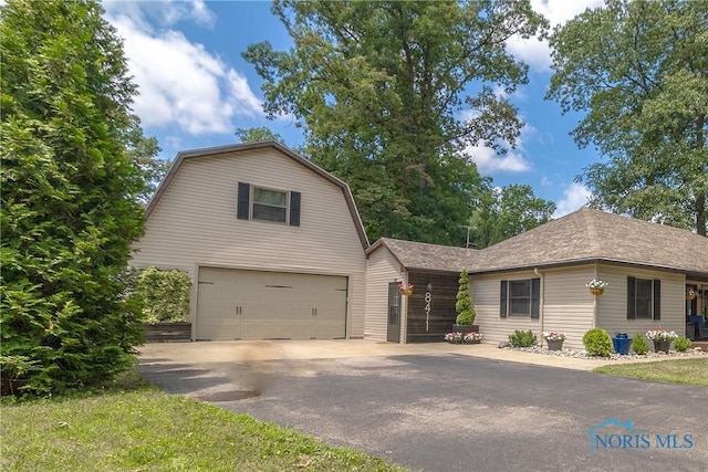 8411 Larch Rd, Toledo, OH 43617 - view of front facade with a gambrel roof, an attached garage, driveway, and roof with shingles