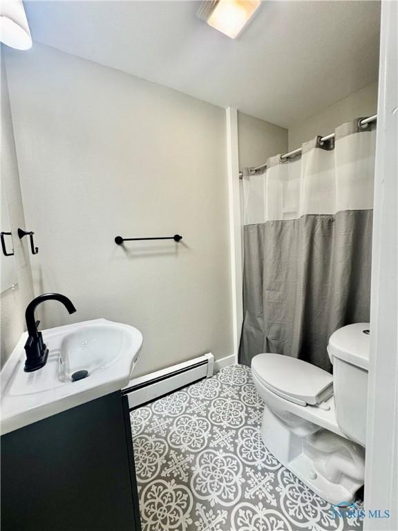 339 N E Ave, Deshler, OH 43516 - bathroom featuring vanity, tile patterned floors, baseboard heating, and a shower with curtain