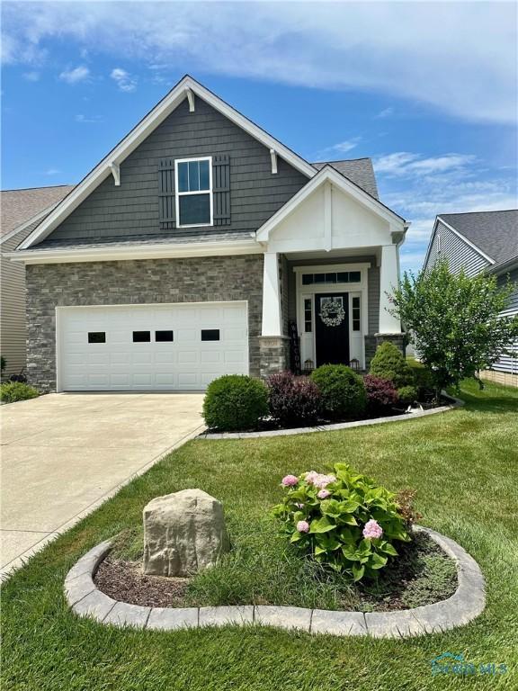 8904 N Park Lake Cir, Sylvania, OH 43560 - craftsman-style house with driveway, a front lawn, stone siding, and a garage