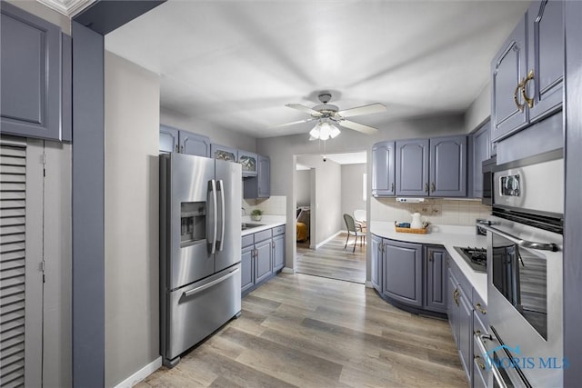5201 Arbor Way, Sylvania, OH 43560 - kitchen with stainless steel appliances, decorative backsplash, light countertops, ceiling fan, and light wood finished floors