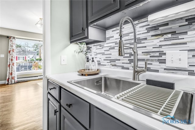 3122 Winston Blvd, Toledo, OH 43614 - kitchen featuring backsplash, light countertops, light wood-style floors, a baseboard heating unit, and gray cabinets