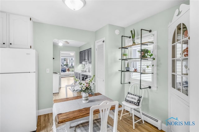 3122 Winston Blvd, Toledo, OH 43614 - dining room with a baseboard heating unit, light wood-type flooring, a ceiling fan, and washing machine and clothes dryer