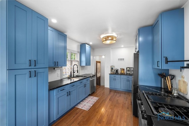 3740 Mapleway Dr, Toledo, OH 43614 - kitchen with blue cabinets, stainless steel appliances, dark countertops, wood finished floors, and recessed lighting