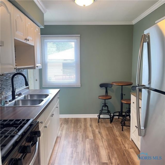 415 W Northgate Pkwy, Toledo, OH 43612 - kitchen with appliances with stainless steel finishes, white cabinetry, light wood-style flooring, backsplash, and crown molding