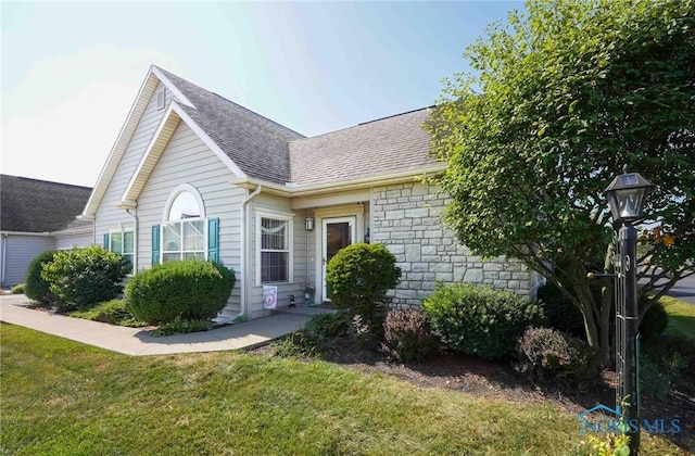 7673 Brookstone Dr Unit U7673, Findlay, OH 45840 - view of front of property featuring roof with shingles, stone siding, and a front yard