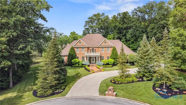 1616 Firestone Dr, Findlay, OH 45840 - colonial-style house featuring a balcony, curved driveway, a front lawn, brick siding, and french doors
