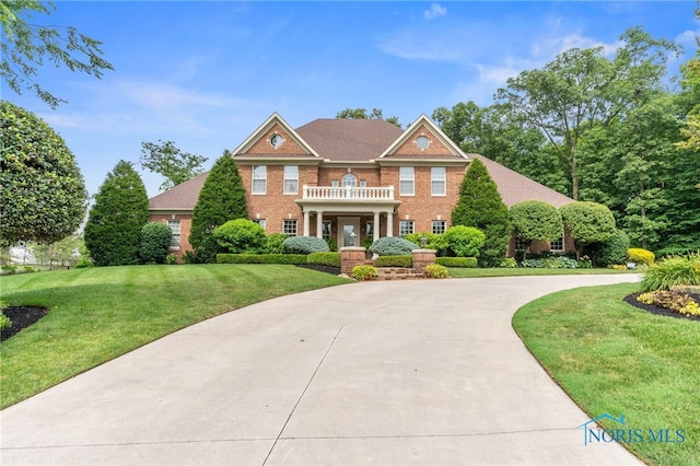 1616 Firestone Dr, Findlay, OH 45840 - colonial inspired home with a balcony, a front lawn, brick siding, and curved driveway