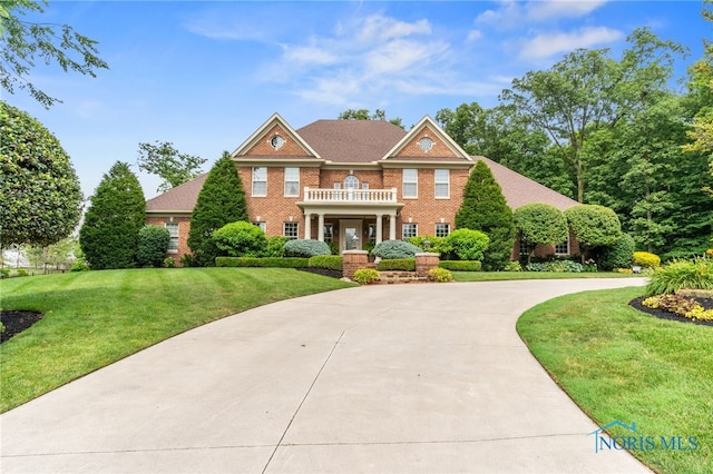 1616 Firestone Dr, Findlay, OH 45840 - colonial house with a balcony, a front lawn, brick siding, and curved driveway
