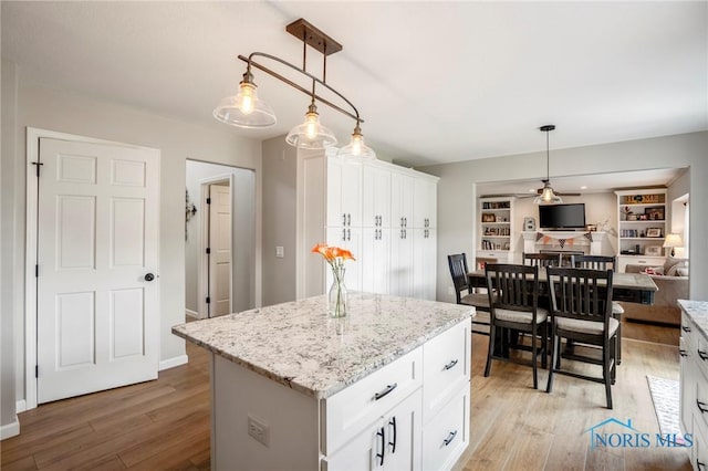 2838 Long View Dr, Maumee, OH 43537 - kitchen with light wood-style flooring, a kitchen island, white cabinetry, and decorative light fixtures
