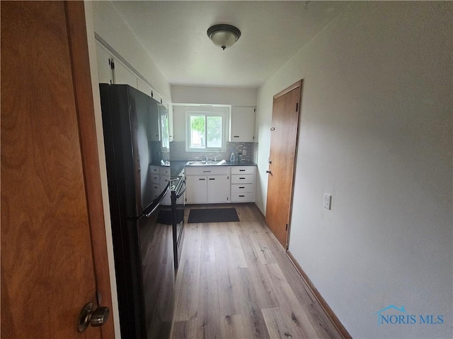 2916 Upton Ave, Toledo, OH 43606 - kitchen with freestanding refrigerator, light wood finished floors, white cabinets, and decorative backsplash
