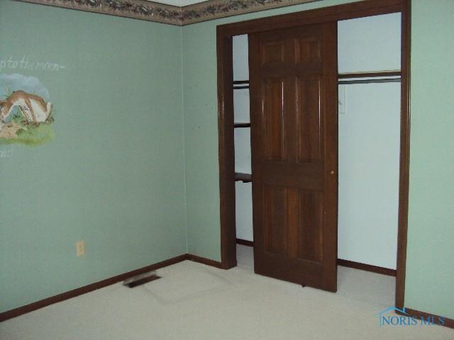 217 Lakeview Dr, Bryan, OH 43506 - unfurnished bedroom with baseboards and light colored carpet