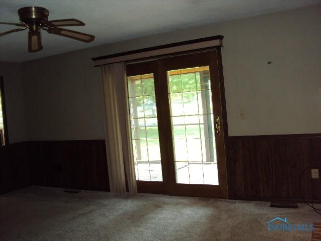 217 Lakeview Dr, Bryan, OH 43506 - empty room with wainscoting, carpet flooring, a ceiling fan, and wooden walls