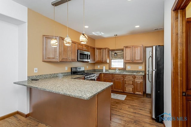 1333 Abbott Ave, Toledo, OH 43614 - kitchen featuring a peninsula, appliances with stainless steel finishes, dark wood-style floors, brown cabinets, and recessed lighting