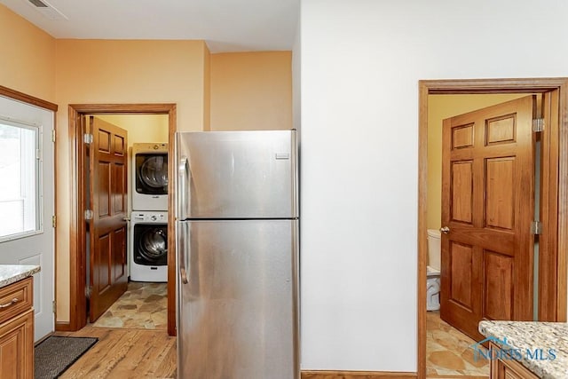 1333 Abbott Ave, Toledo, OH 43614 - kitchen with stacked washer / dryer, freestanding refrigerator, light stone countertops, and light wood-style flooring