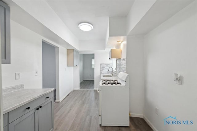 1155 Pinewood Ave, Toledo, OH 43607 - kitchen featuring white range with gas cooktop, light countertops, wood finished floors, and gray cabinetry