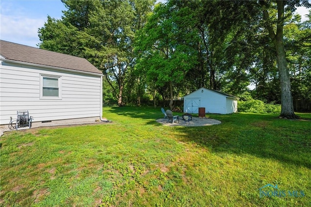 6006 Blossman Rd, Toledo, OH 43617 - view of grassy yard featuring an outdoor structure, a fire pit, and a patio