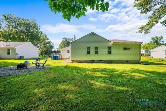 6006 Blossman Rd, Toledo, OH 43617 - back of property featuring an outdoor fire pit, a lawn, and crawl space