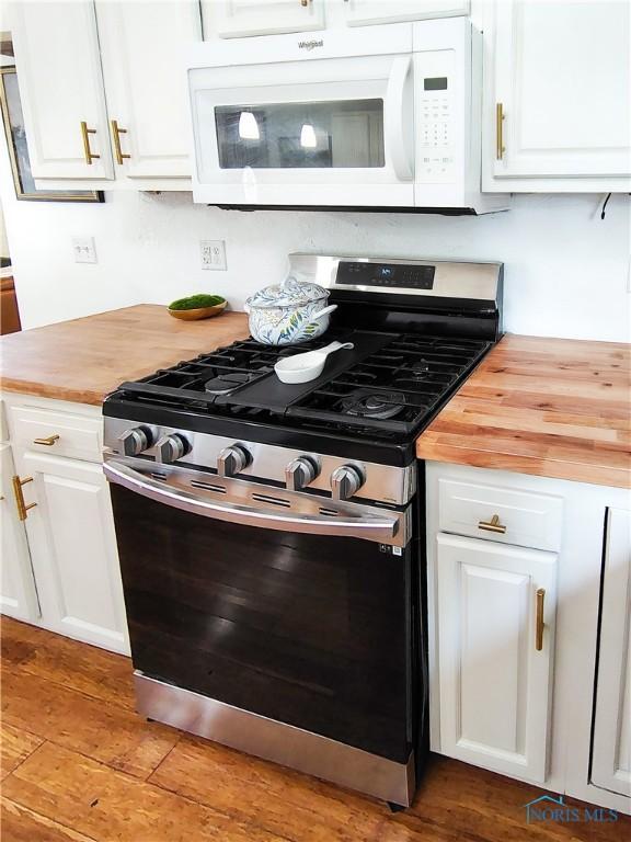 15740 Hill Rd, Defiance, OH 43512 - kitchen with stainless steel gas range oven, white microwave, butcher block counters, and white cabinets