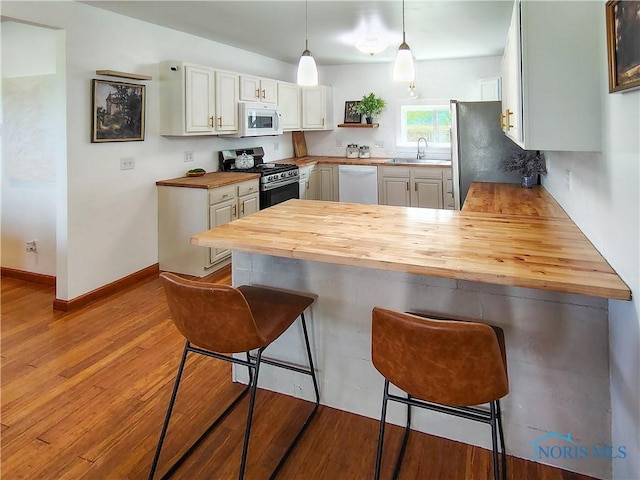 15740 Hill Rd, Defiance, OH 43512 - kitchen with stainless steel appliances, wood counters, a peninsula, wood finished floors, and a breakfast bar area