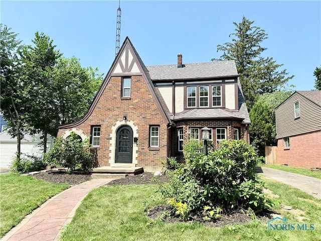 2515 Densmore Dr, Toledo, OH 43606 - english style home featuring brick siding, a front yard, a chimney, and a shingled roof