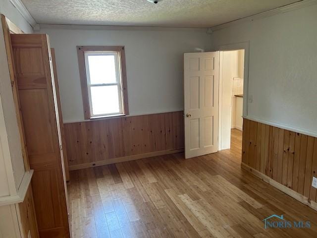 203 S Main, Hicksville, OH 43526 - unfurnished room featuring a wainscoted wall, wood finished floors, wood walls, a textured ceiling, and ornamental molding
