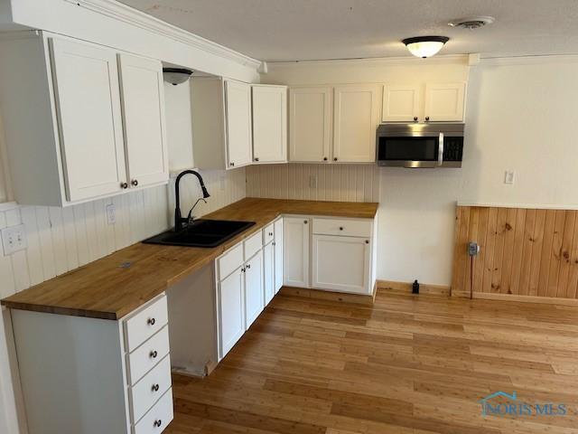 203 S Main, Hicksville, OH 43526 - kitchen featuring wood counters, light wood finished floors, white cabinets, wooden walls, and wainscoting