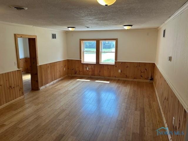 203 S Main, Hicksville, OH 43526 - unfurnished room with wainscoting, wood finished floors, wooden walls, and a textured ceiling