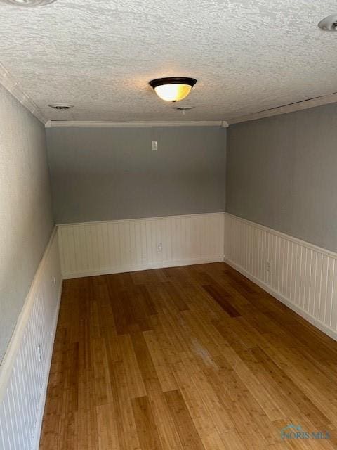 203 S Main, Hicksville, OH 43526 - spare room with ornamental molding, wood finished floors, wainscoting, and a textured ceiling